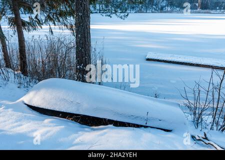 un bateau à l'envers recouvert de neige près d'un lac gelé Banque D'Images