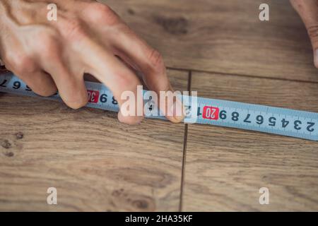 Homme installant un nouveau parquet stratifié en bois sur un plancher de film chaud.Système de chauffage au sol infrarouge sous sol stratifié Banque D'Images