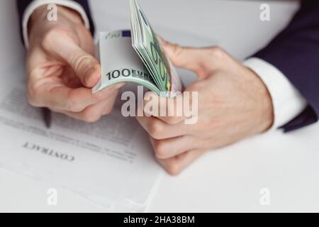L'homme en costume compte de l'argent avant de signer le contrat.Gros plan avec de l'argent euro Banque D'Images