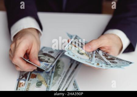 Homme d'affaires mains en costume comptant argent comptant US dollars sur table blanche Banque D'Images