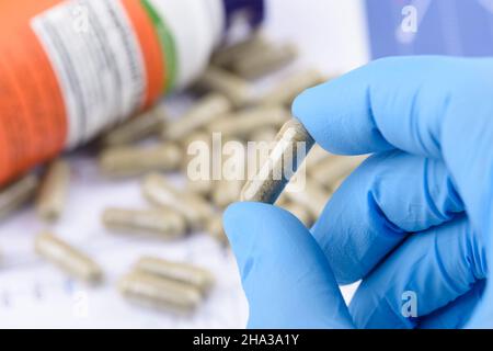 Compléter la capsule dans les mains des scientifiques, avec une bouteille et des pilules sur le fond. Banque D'Images