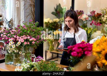 affaires, technologie, vente et fleuriste et concept. fleuriste femme avec ordinateur tablette pc au comptoir fleuriste. jeune fleuriste gentil utilisant le numérique t Banque D'Images