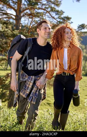 Couple romantique marchant dans un champ de forêt de conte de fées. Les touristes caucasiens font une pause lors de la randonnée dans les bois. Femme et homme sympathiques tenant les mains ensemble Banque D'Images