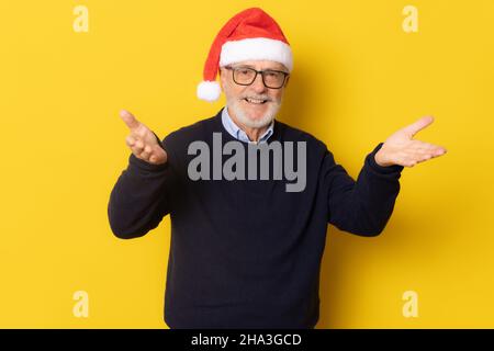 Homme souriant senior portant un chapeau de père noël isolé sur fond jaune. Banque D'Images