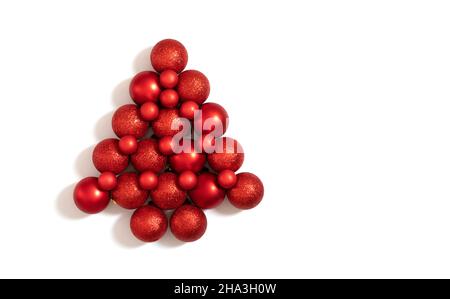 Boules rouges de Noël disposées en forme d'arbre de Noël.Décorations du nouvel an isolées sur fond blanc.Vue de dessus, plan d'appartement. Banque D'Images