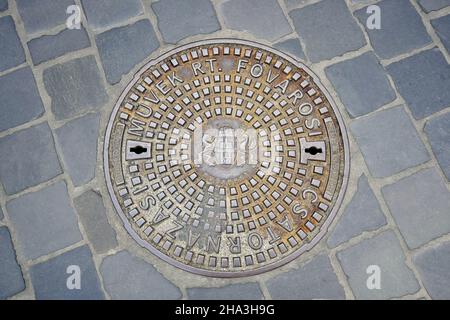 Couverture de trou d'homme en fonte ornementée à Budapest, Hongrie.Gros plan de la couverture de trou d'homme de conduit avec les armoiries de Budapest dans le quartier de la vieille ville.Égouts Banque D'Images