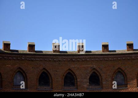 Ancien bâtiment en brique avec fenêtres en forme d'arche sur fond de ciel bleu sans nuages.Gros plan.Mise au point sélective.Copier l'espace. Banque D'Images