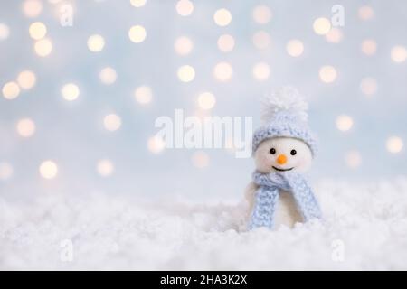 Jouet bonhomme de neige sur un fond d'hiver de Noël avec espace de copie.Carte de vœux de Noël et du nouvel an.Bonhomme de neige dans un chapeau bleu. Banque D'Images