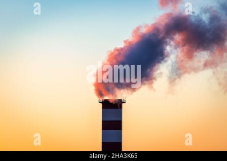 Cheminée de la chaufferie avec de la fumée qui en sort sur le fond du ciel. Banque D'Images