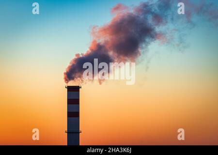 Cheminée de la chaufferie avec de la fumée qui en sort sur le fond du ciel. Banque D'Images