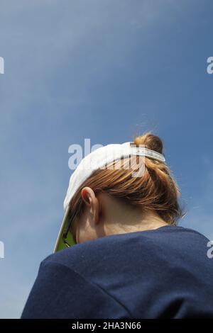 Vue arrière d'une femme sportive portant un sweat-shirt bleu foncé et une casquette blanche Banque D'Images
