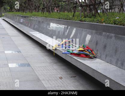 Un tas de multiconducteurs ont abandonné le parapluie brisé et l'ont jeté sur le siège mural. Banque D'Images