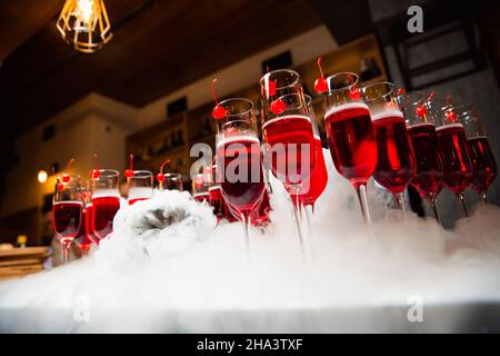 Des verres avec une boisson rouge sont sur le bar le verre est décoré de cerises Banque D'Images