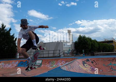 Jeune garçon blond patineur hispanique à poil long pratiquant le skateboard et le saut avec son skateboard Banque D'Images