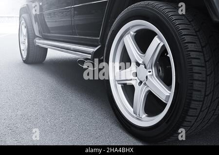 Les roues d'une voiture se rapprochent sur fond d'asphalte.Pneus de voiture.Gros plan de roue de voiture. Pour la publicité (pour la publicité) Banque D'Images