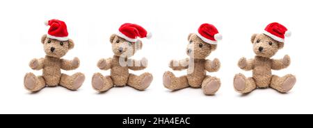 quatre ours en peluche avec chapeaux de père noël assis sur fond blanc Banque D'Images