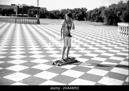 skater fille de patinage et de saut sur terrazza mascagni à livourne, en italie. son grand belvédère sinueux vers la mer avec une surface pavée de 8700 m² comme un damier et 4,100 balusters Banque D'Images