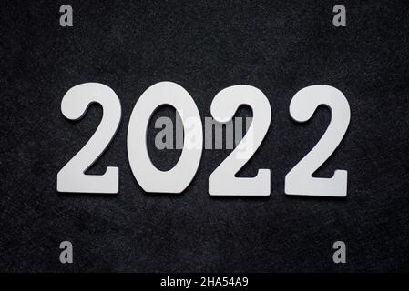 Panneau du nouvel an 2022 en bois sur fond festif avec espace pour les copies.Le bois peint en blanc a créé l'inscription numéro 2022 sur fond noir. Banque D'Images