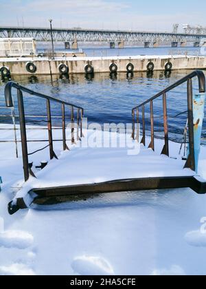 Vue d'hiver sur les jetées de rivière abandonnées sur le Dniepr.Des bornes rouillées dans la neige.Les jetées sont couvertes de neige. Banque D'Images