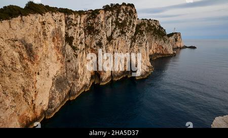 grèce,îles grecques,îles ioniennes,lefakada ou lefkas,pointe sud de l'île,côte escarpée,cap lefkadas,lumière de l'après-midi,petit soleil,vue sur tout le cap à la pointe sud avec phare,vue grand angle,eau sombre,ciel bleu avec bandes blanches de nuages,humeur sombre Banque D'Images