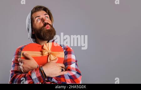 Boîte cadeau en forme de coeur pour homme barbu.Cadeau avec amour.L'heure des cadeaux.Saint-Valentin.Copier l'espace Banque D'Images