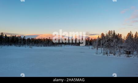 huttes dans la forêt, lac couvert de neige, derrière le pallastunturi, yli-kyrö, laponie, finlande Banque D'Images