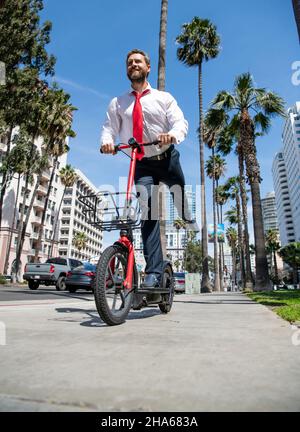 Démarrage en ligne.Un homme heureux en scooter électronique dans la rue.Démarrage en ligne.Transport électrique Banque D'Images