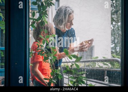 Vue par la fenêtre sale de la mère et du fils communiquant sur le balcon Banque D'Images