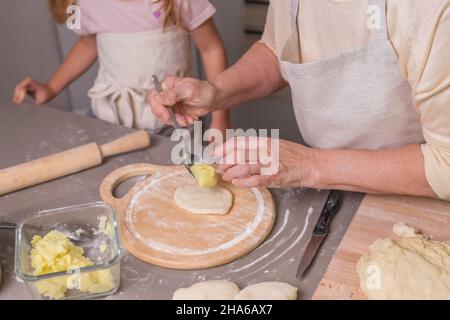 Les mains des grands-mères et des petites-filles préparent un plat traditionnel russe Banque D'Images