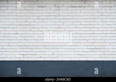 Mur de briques blanchi à la chaux blanche avec plinthe bleu foncé Banque D'Images