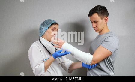 Le médecin de Brunette examine l'avant-bras cassé du jeune homme Banque D'Images