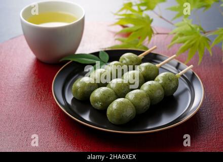 Boulettes d'herbe et thé vert placées sur un plateau japonais rouge Banque D'Images