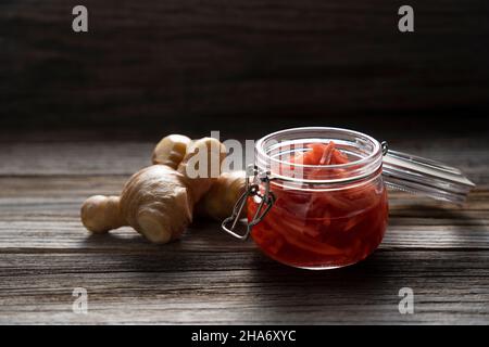 Gingembre mariné rouge dans un pot en verre placé sur un fond en bois ancien. Banque D'Images