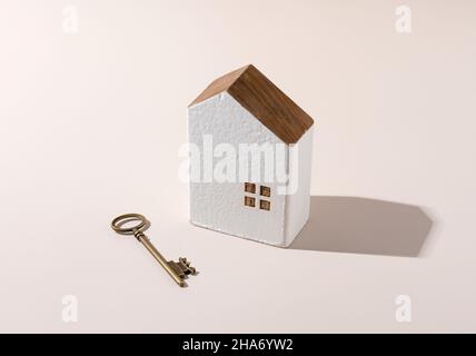 Modèle d'une maison avec des clés en laiton placées sur un fond beige.Concept de sécurité et de vente de maison. Banque D'Images