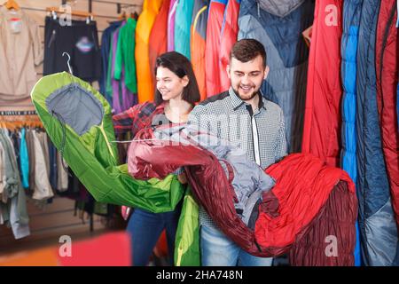 Smiling couple l'examen de divers sacs de couchage au magasin d'équipement de sport Banque D'Images