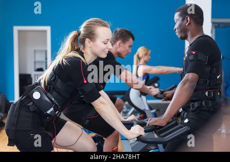 .les gars et les filles exécutant l'entraînement de stimulation musculaire électrique de tout le corps dans le club de santé Banque D'Images