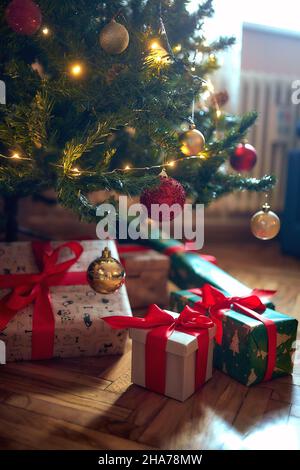 Noël emballé présente sous l'arbre lors d'une soirée de Noël Banque D'Images