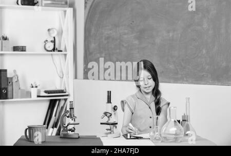 Formation en biologie. Leçon de science. Laboratoire scolaire. Petite fille au microscope. Tubes de test de classe biologie pour fille. Expérience scientifique. Fascinant Banque D'Images