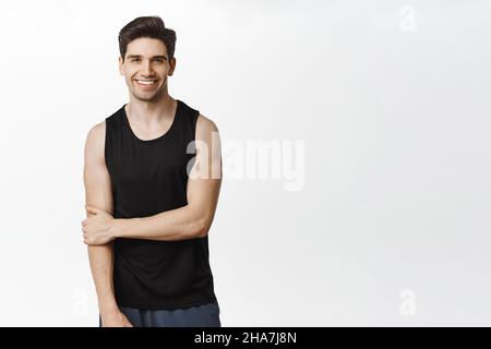 Sport et entraînement.Beau homme souriant posant dans le débardeur sur fond blanc de studio Banque D'Images