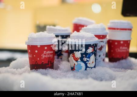 Tasses à café en papier utilisées avec motif de vacances laissées sur un banc enneigé en soirée d'hiver.Boisson chaude de Noël. Banque D'Images