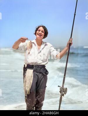 1920S 1930S FEMME SOURIANTE DEBOUT SUR OCEAN BEACH SABLE PORTANT DES WADERS EN CAOUTCHOUC TENANT LE POISSON ET LA CANNE DE PÊCHE DE SURF REGARDANTAPPAREIL PHOTO - A3598C HAR001 HARS HEUREUX JOIE STYLE DE VIE OCEAN FEMELLES FIERS GROGNUP COPIE ESPACE CAPTURE DEMI-LONGUEUR DAMES PERSONNES ADULTES ATHLÉTIQUEROD SURF EXPRESSIONS BRUNETTE SUCCÈS SHORE COMPÉTENCE ACTIVITÉ AMUSEMENT BONHEUR ENJOUÉ AVENTURE PASSE-TEMPS LOISIR INTÉRÊT EXCITATION PASSE-TEMPS SAVOIR RÉCRÉATIONFIERTÉ PLAISIR LOISIRS PÊCHE SOURIRES JOYEUSE ÉLÉGANTS WADERS PÊCHE EAU SALÉE FEMME MOYENNE-ADULTE DÉTENTE SEASCAPE AMATEUR CAUCASIEN PLAISIR ETHNIQUE HAR001 Banque D'Images