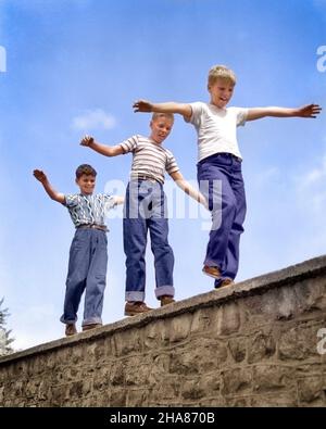 1950S TROIS GARÇONS EN RIANT MARCHANT SUR LE DESSUS DE LA PIERRE MUR DES BRAS DEHORS LE JEU D'ÉQUILIBRAGE SUIVRE LE LEADER - B5606C HAR001HARS STYLE DE VIE SATISFACTION COPIE ESPACE PERSONNES ENFANTS AMITIÉ PLEINE LONGUEUR PERSONNES RISQUE DENIM ÉQUILIBRAGE PRETEEN GARÇON STABILITÉ STRUCTURE GAIE AVENTURE PALSCOURAGE DÉFI EXCITATION LEADERSHIP LOW ANGLE RÉCRÉATION TRIO FIERTÉ PRETTEEN TEE-SHIRTS SUIVRE AMICAL JOYEUX T-SHIRTS BLEU JEANS ÉQUILIBRE SEMELLEJEUNES INFORMELS AVANT L'ADOLESCENCE AVANT L'ADOLESCENCE GARÇON TOGETHERNESS TWERA DÉCONTRACTÉ CAUCASIENS ETHNICITÉ OSER HAR001 VIEUX MODE Banque D'Images