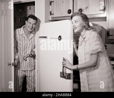 1950S COLLATIONS DE MINUIT FEMME DANS LA CHEMISE DE NUIT OUVERTURE DE LA PORTE DU RÉFRIGÉRATEUR ET MARI DANS LE PYJAMA PIQUANT DANS LA CUISINE - H2827DEB001 HARS 1 SILLY FACIAL COMIC HEUREUX JOIE STYLE DE VIE SATISFACTION FEMMES MARIÉE CONJOINT ÉPOUX SAINTETÉ VIE VIE COPIE ESPACE AMITIÉDEMI-LONGUEUR FEMMES PERSONNES HOMMES PYJAMA EXPRESSIONS B&W PARTENAIRE SNACKS HUMORISTIQUE BONHEUR FAIM GAI ET COMIQUE ATTRAPÉ OCCASION CHEMISE DE NUIT SOURIRE CONNEXIONCOMÉDIE NOCTURNE JOYEUSE MINUIT DEB001 ADULTE MOYEN-ADULTE HOMME TOGETHERNESS ÉPOUSES NOIR ET BLANC CAUCASIEN ETHNICITÉ ANCIEN MODE RAUDING Banque D'Images