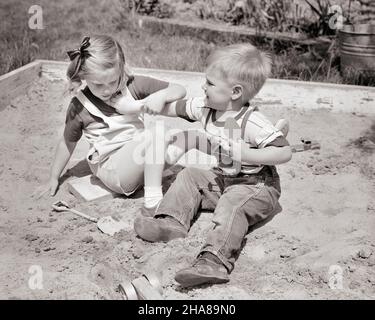 1950S ANGRY BOY FRÈRE POUSSANT FILLE SOEUR DANS LA BOÎTE DE SABLE COMME ILS ARGUENT SUR LES OUTILS DE JOUET - J6485 HAR001 HARSVIEUX TEMPS NOSTALGIE FRÈRE VIEILLE MODE SŒUR 1 STYLE JUVÉNILE COLÈRE PEUR BLONDE ABUS SÉCURITÉ CONCURRENCE COTON CONFLIT AGACÉ FEMMESFRÈRES PERSONNES LES HOMMES RISQUENT LA VIOLENCE FRÈRES ET SŒURS DENIM SŒURS B&W ÉTÉ VICTIME REBUTS AFFLIGÉ ET EXCITATION MASCULINE FRÈRE/SŒUR VIOLENCE DÉPLAISIR VIOLENTHOSTILITÉ ANGRLY AGRESSIVE ENNUI BLEU JEANS ÉMOTION ÉMOTIONNELLE INFORMELLE IRRITÉ JUVÉNILES QUARREL SAISON SANDBOX TWERA AGRESSION NOIR ET BLANC DÉCONTRACTÉORIGINE ETHNIQUE CAUCASIENNE MÉCONTENTIE HAR001 Banque D'Images