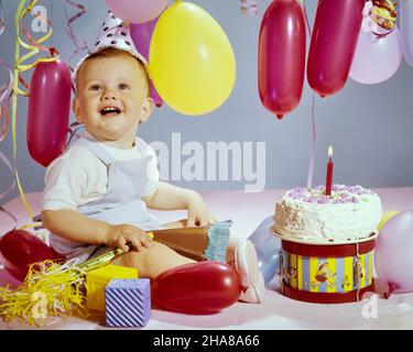 1960S SOURIRE RIANT BÉBÉ GARÇON REGARDANT ASSIS À CÔTÉ DU GÂTEAU D'ANNIVERSAIRE AVEC UN AN BOUGIE ROUGE ET BALLONS JAUNES ETSTREAMERS - KB4495 HAR001 HARS HEUREUX JOIE STYLE DE VIE CÉLÉBRATION STREAMERS STUDIO SHOT SAINTETÉ MAISON VIE COPIE ESPACE HOMMES EXPRESSIONS SUCCÈSBONHEUR GAI ET EXCITATION SOURIT CONCEPTUEL À CÔTÉ DE JOYEUX BÉBÉ GARÇON ÉLÉGANT JEUNES UN AN CAUCASIEN ETHNICITÉ HAR001 ANSÀ LA MODE Banque D'Images