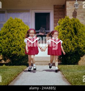 1960S TWIN FILLES PORTANT DES ROBES ROUGES MARY JANE CHAUSSURES COURANT SUR LE TROTTOIR DE LA MAISON TENANT LES MAINS SOURIANTES - KJ3689 HAR001HARS DOUBLE JOIE HEUREUSE FEMMES CORRESPONDENT SŒURS BIENVENUES SŒURS EXPRESSIONS ROBES CORRESPONDANT À LA MÊME JOYEUSE MARY JANE TENANT DES MAINS FRÈRES SOURIRESJOVIFUL LOOK-SEMBLABLES ATTACHEMENT PERSONNEL AFFECTION DUPLIQUÉE ÉMOTION LES JEUNES RESSEMBLENT CAUCASIENS ETHNICITÉ CLONE HAR001 OLD FASHIED Banque D'Images