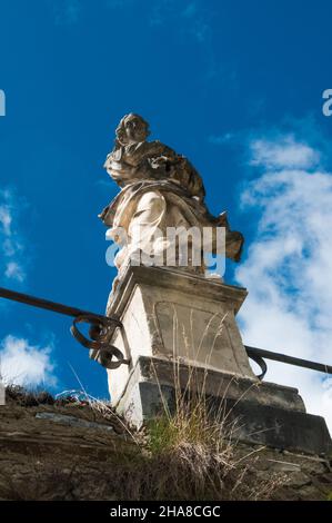 Vue de dessous d'une statue femelle debout sur un piédestal contre un ciel bleu clair Banque D'Images