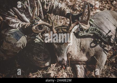 Un adolescent tenant un buck de 8 points mort se dirige vers le haut dans les bois du Wisconsin Banque D'Images