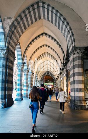 Personnes marchant sous l'arcade dans le style gothique de la via XX Settembre, une des rues principales de Gênes, Ligurie, Italie Banque D'Images