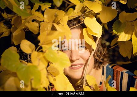 Femme souriante parmi les feuilles jaunes d'automne au parc général San Martin dans la province de Mendoza, en Argentine. Banque D'Images